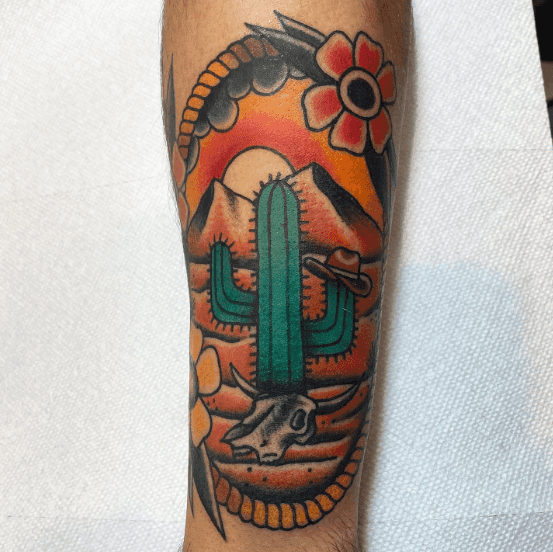 A tattoo of a cactus with a western themed backdrop.