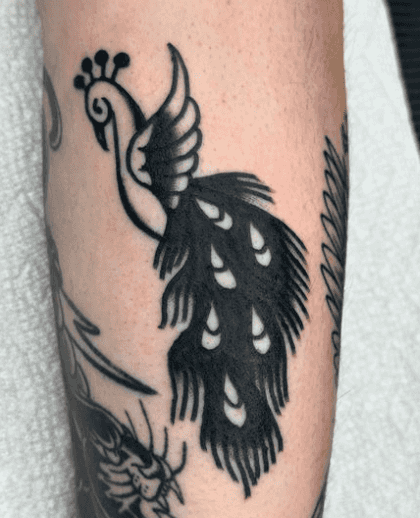 A black and white tattoo of a majestic peacock.