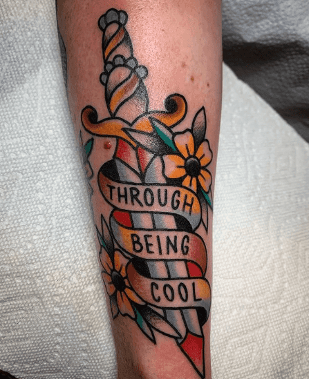 A tattoo of a dagger with a banner that says "Through Being Cool".