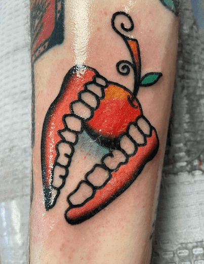 A tattoo of a set of false teeth biting into a piece of fruit.