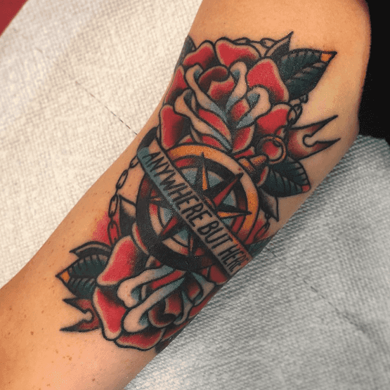 A tattoo of a compass set against two roses.