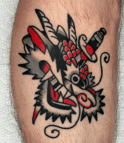 A tattoo of a red dragon with a dagger through it's head.