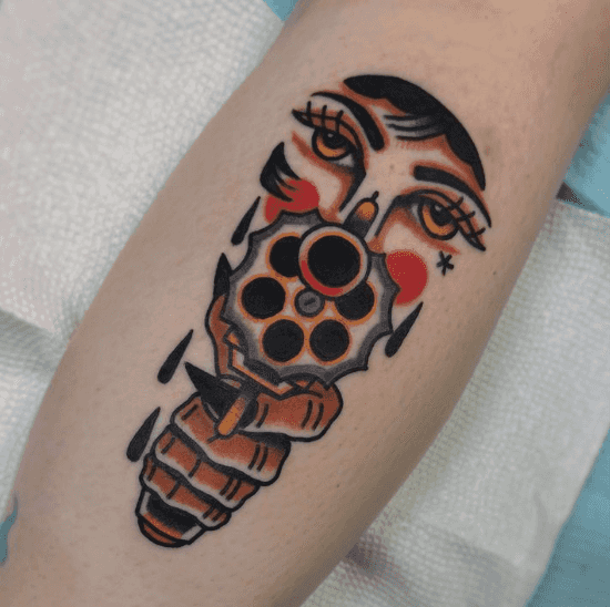 A tattoo of a person's hand and eyes, who is pointing a gun toward the viewer.