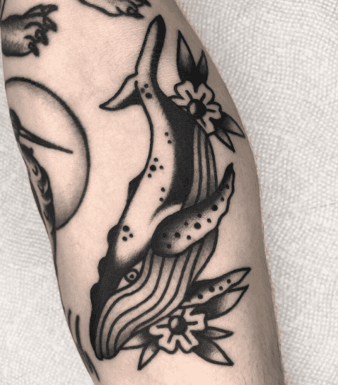 A black and white tattoo of a whale.