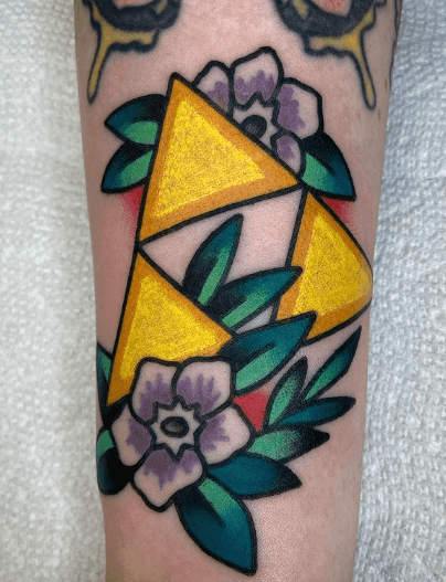 A tattoo of a the Triforce from Zelda set against decorative flowers.