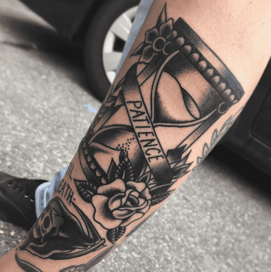 A black and white tattoo of an hourglass.