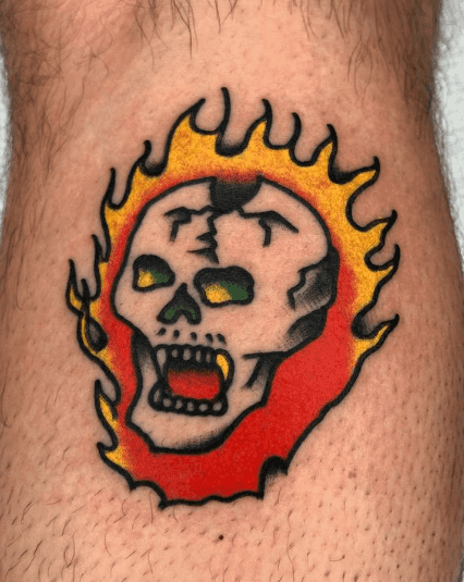 A tattoo of a fanged skull on fire.